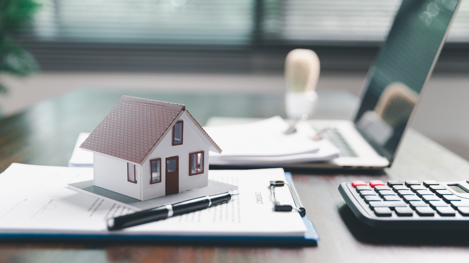 Mini house model with property tax documents beneath