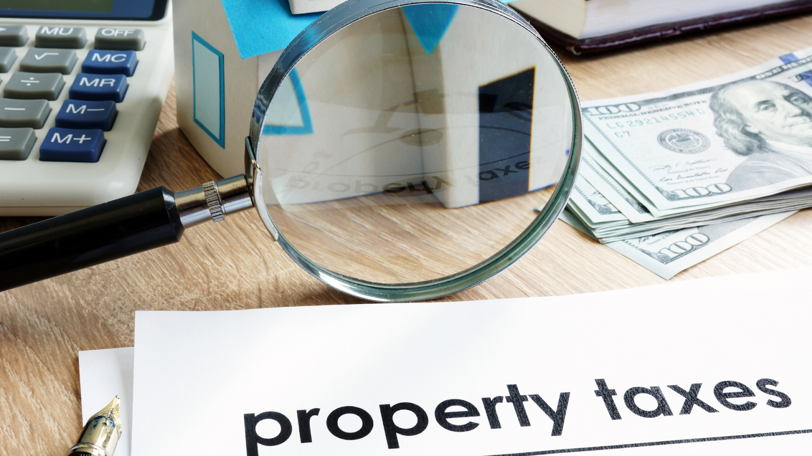 Property tax documents with cash, calculator, and magnified house model