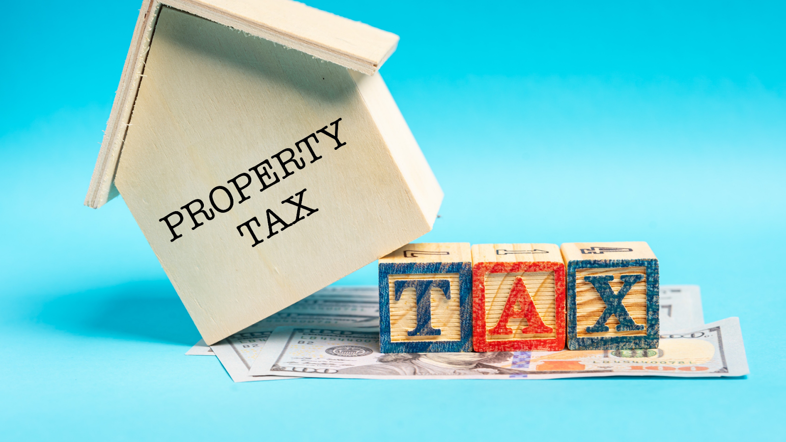 Property tax printed on mini wooden home with tax blocks and cash under