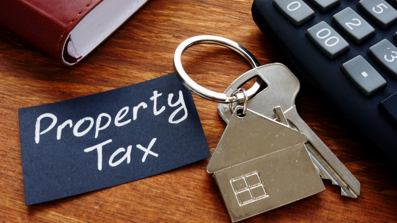 Property tax written on black paper with key, calculator, and a workbook