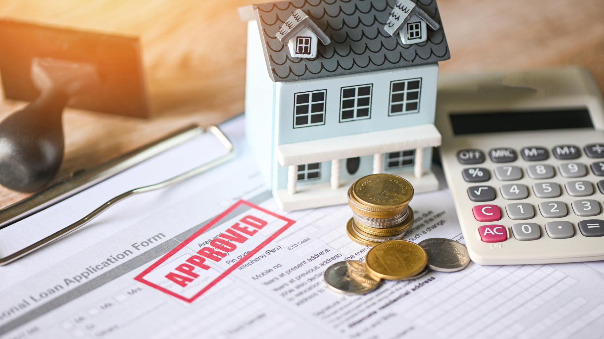 Approved home loan application beside a small house model