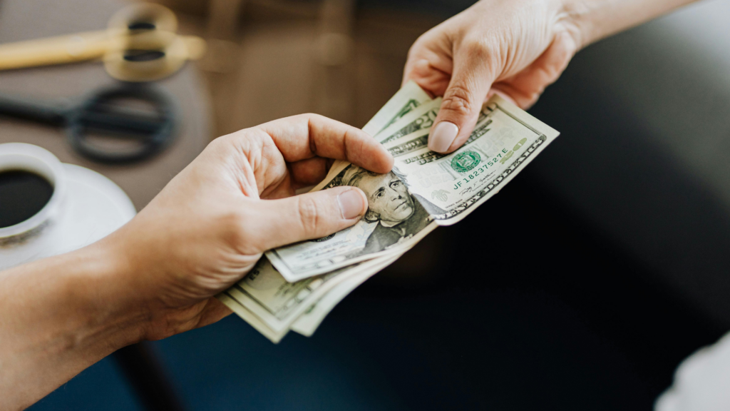 Hands passing dollars symbolizing consistent home equity loan payments