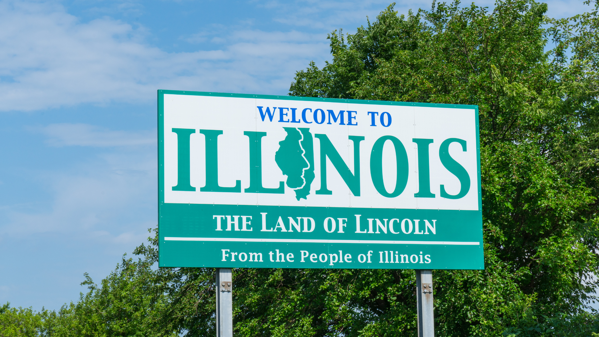 The official Illinois state welcome sign surrounded by green trees