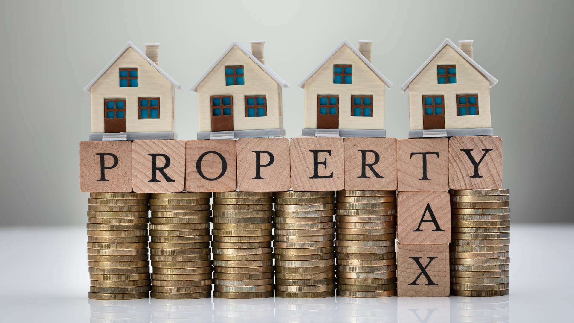 Property tax concept with house models stacked on coins and blocks