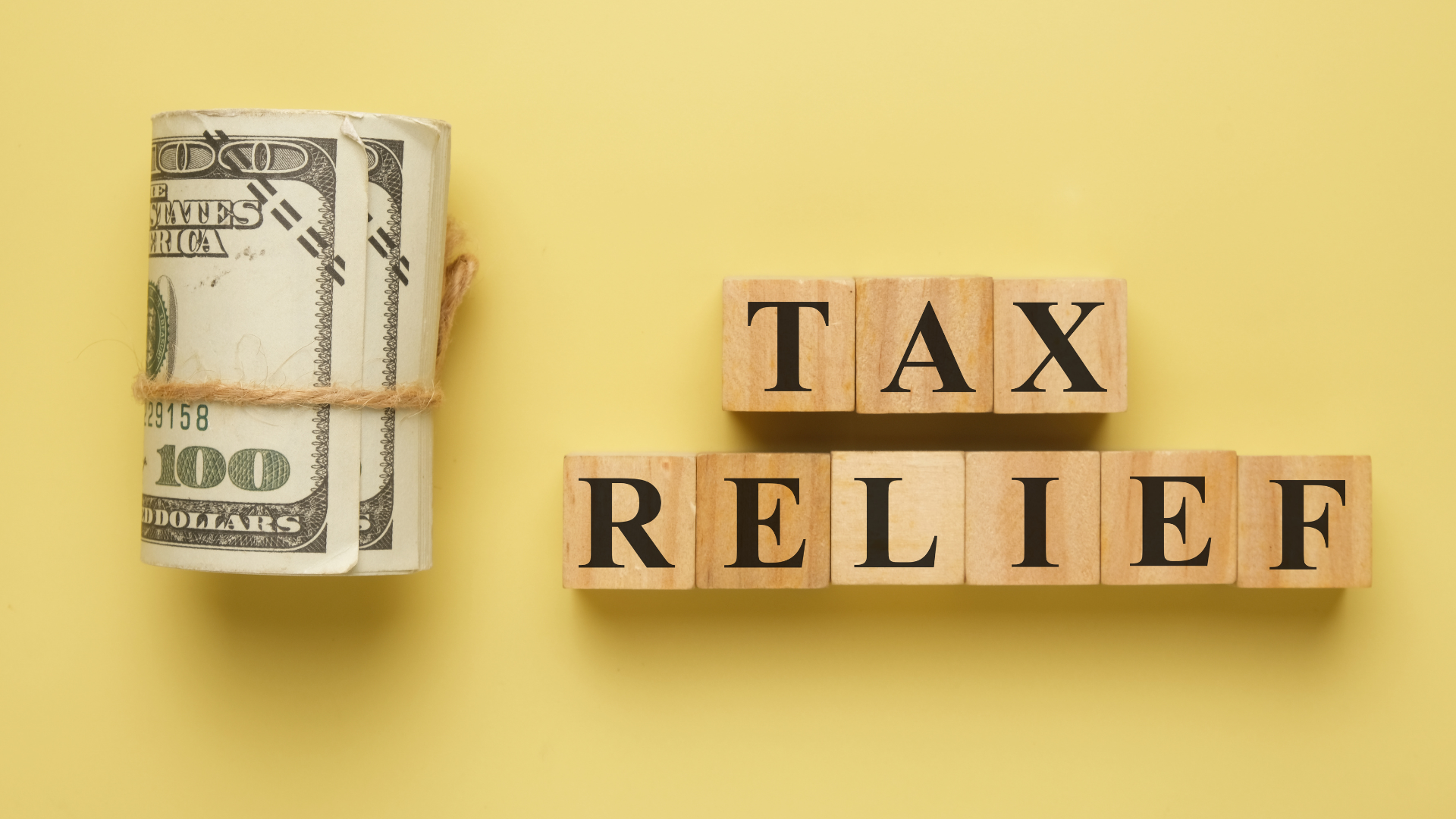 Tax relief concept showing cash and wooden letter blocks