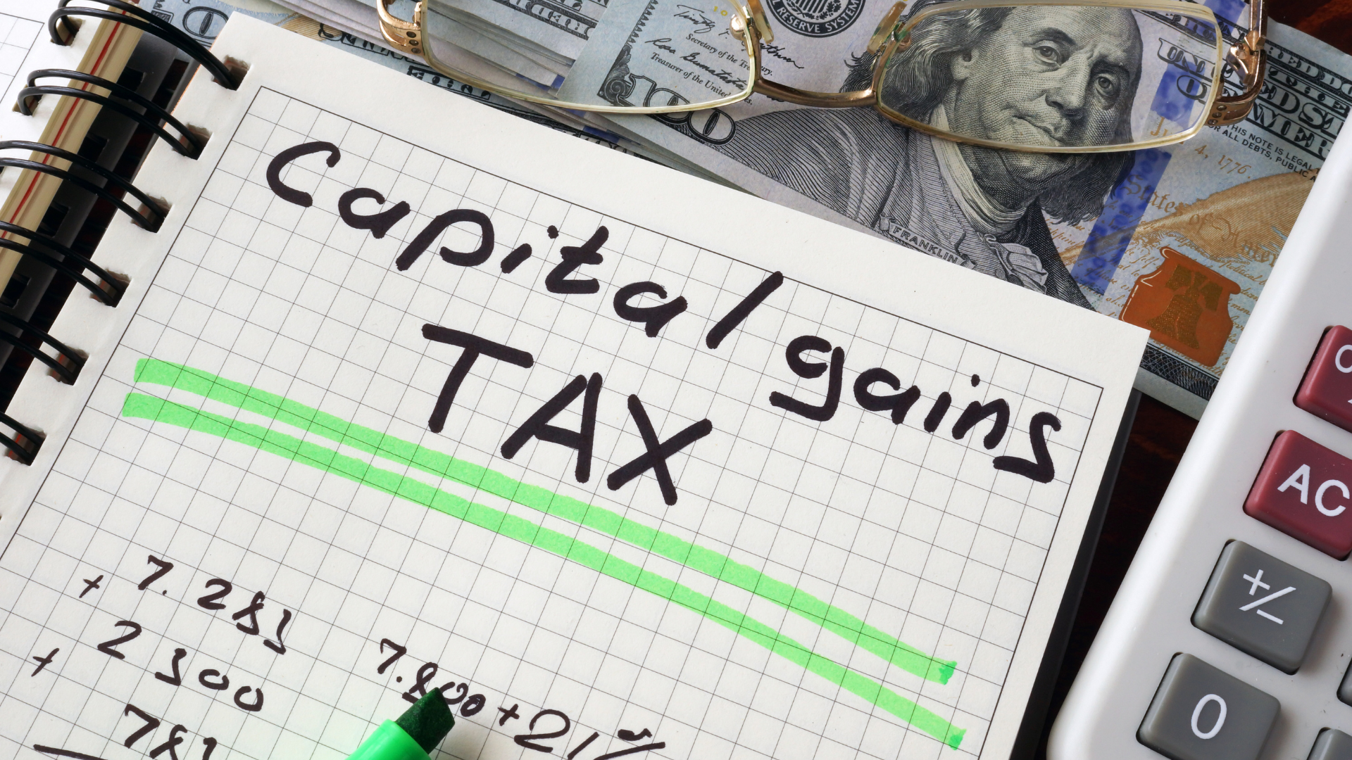 Capital gains tax written in notebook next to cash and calculator