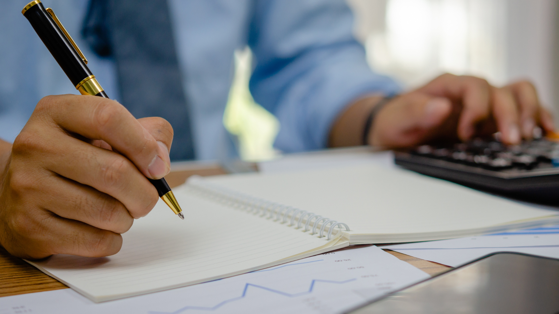Close up of a hand drafting notes alongside property tax appeal charts
