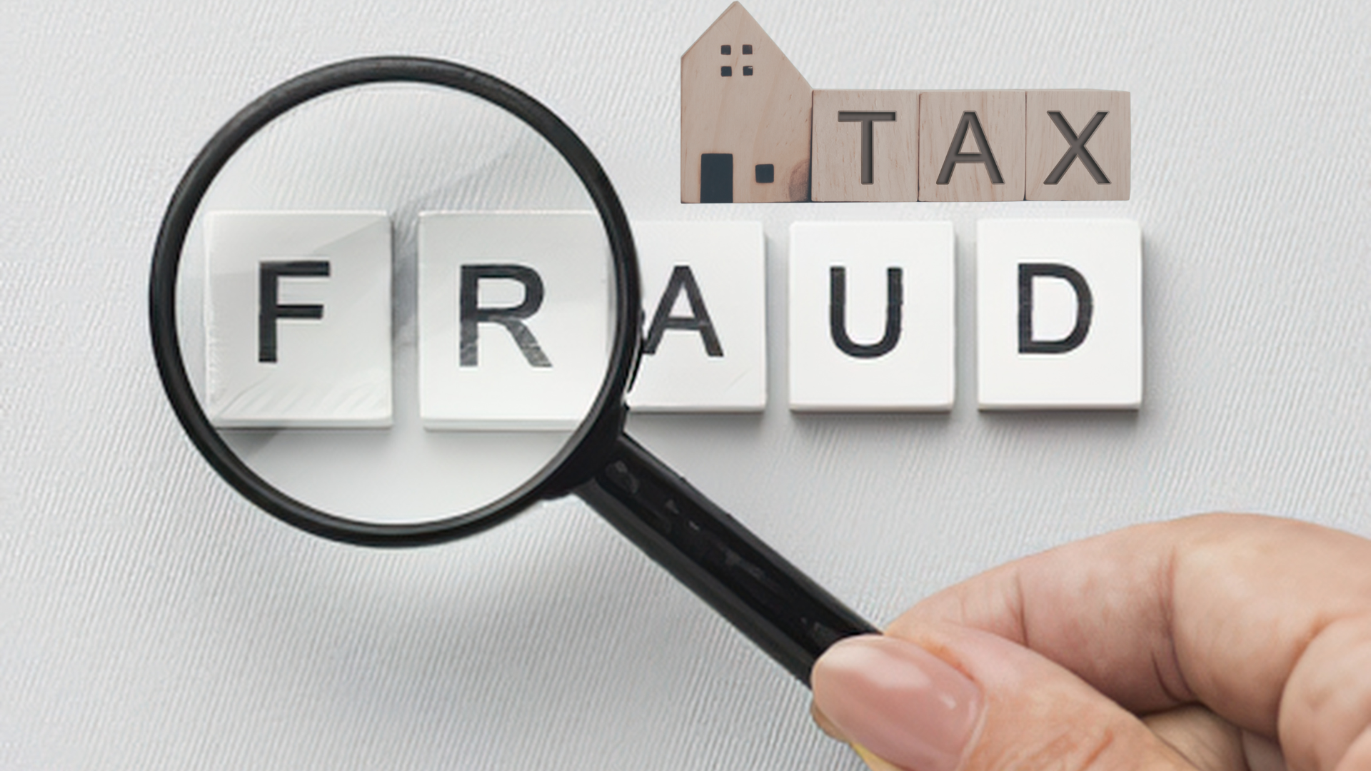 Magnifying glass over tax fraud tiles uncovering property tax fraud schemes