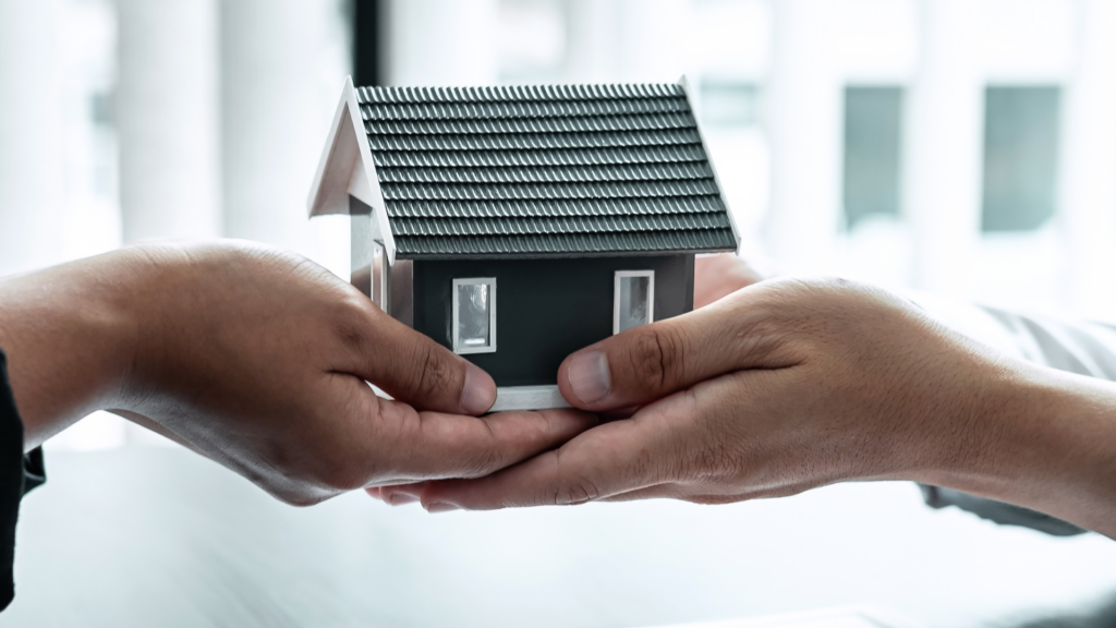 Person handing over property model as a charitable estate planning contribution