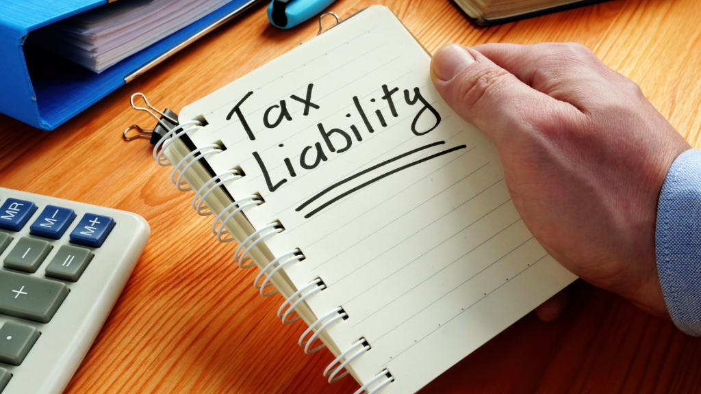 Tax liability calculation notes beside a calculator during a property sale